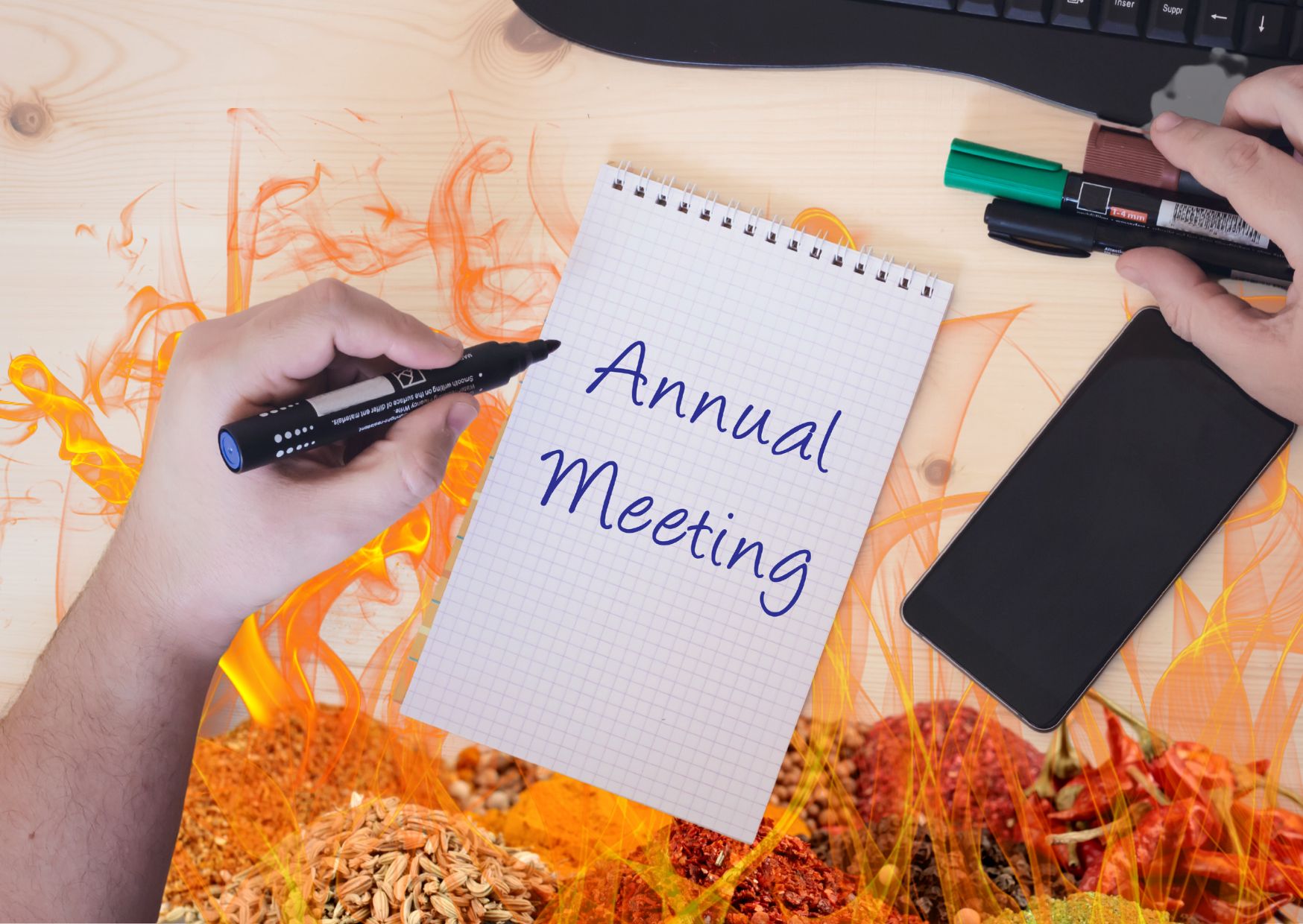 Annual general meeting written on a notepad with fire and spices in the background