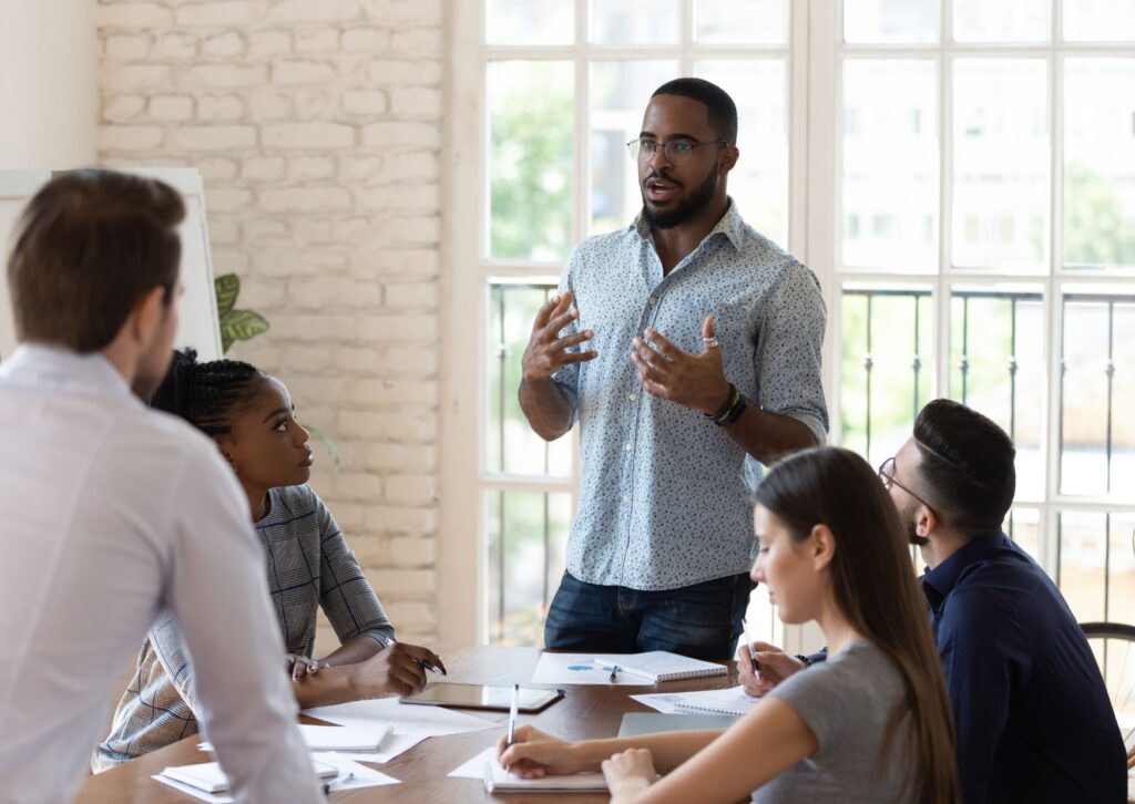 Black man standing up talking to his colleagues