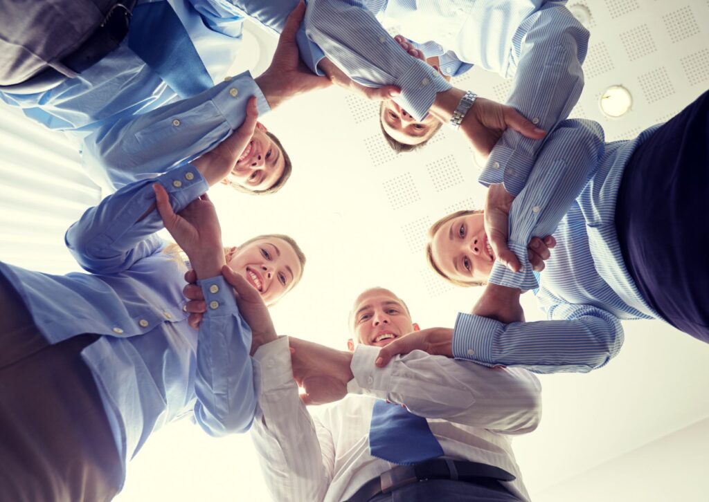 employees-standing-in-a-circle-holding-arms