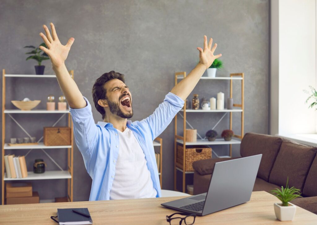 happy-man-at-work-desk-with-arms-in-the-air-rejuvenated