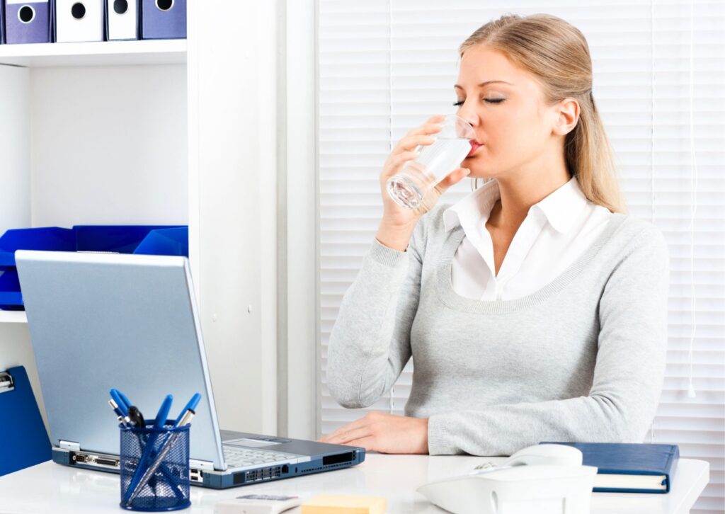 lady-drinking-water-while-working-from-home-at-her-desk