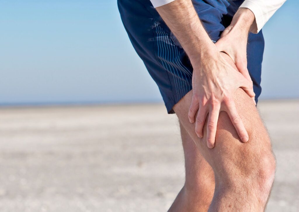 man holding his leg with cramp