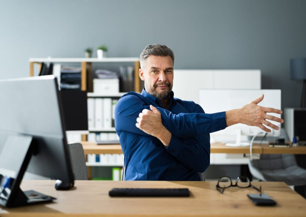 Man stretching his right shoulder while working from home